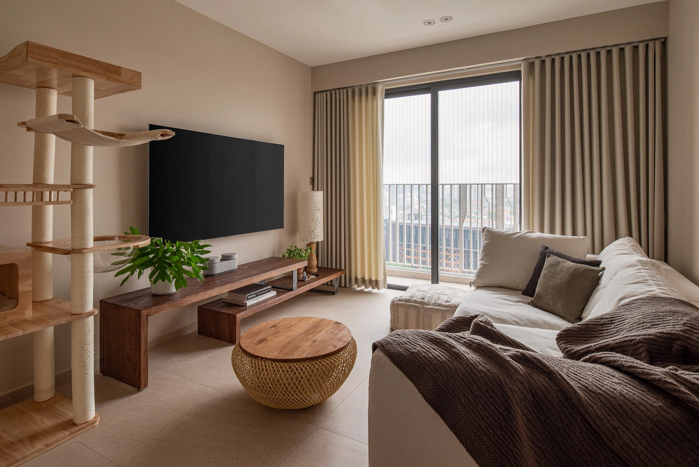 Modern living room with wooden furniture, balcony, and white sofa with throws and cushions