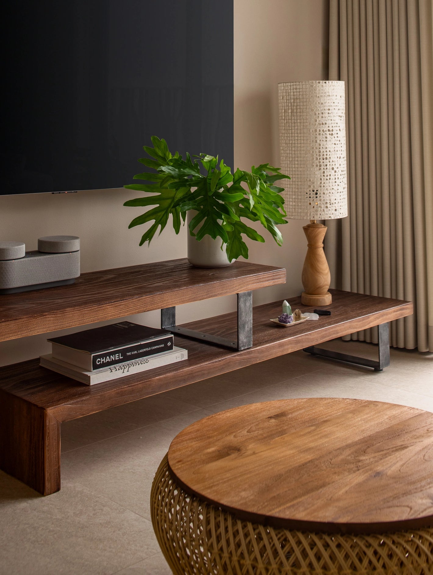 Modern living room with wooden TV console, rattan coffee table, and table lamp