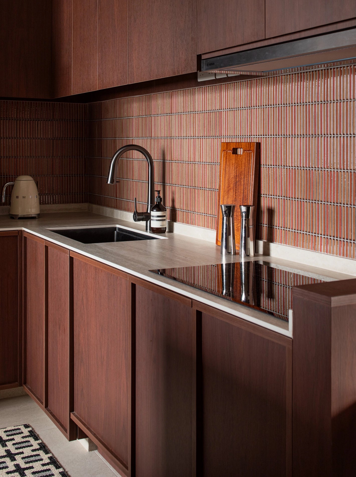 Mid-century modern kitchen with wooden table, red Kit Kat tiles, and stone countertop
