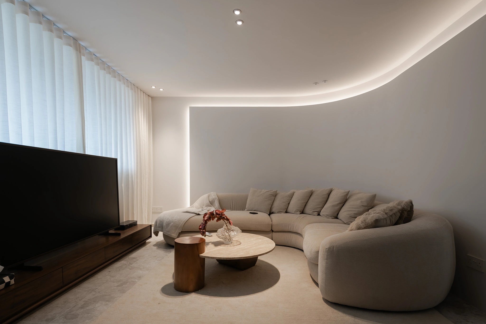 Modern living room with curved sofa, curved feature wall, walnut coffee table with stone top