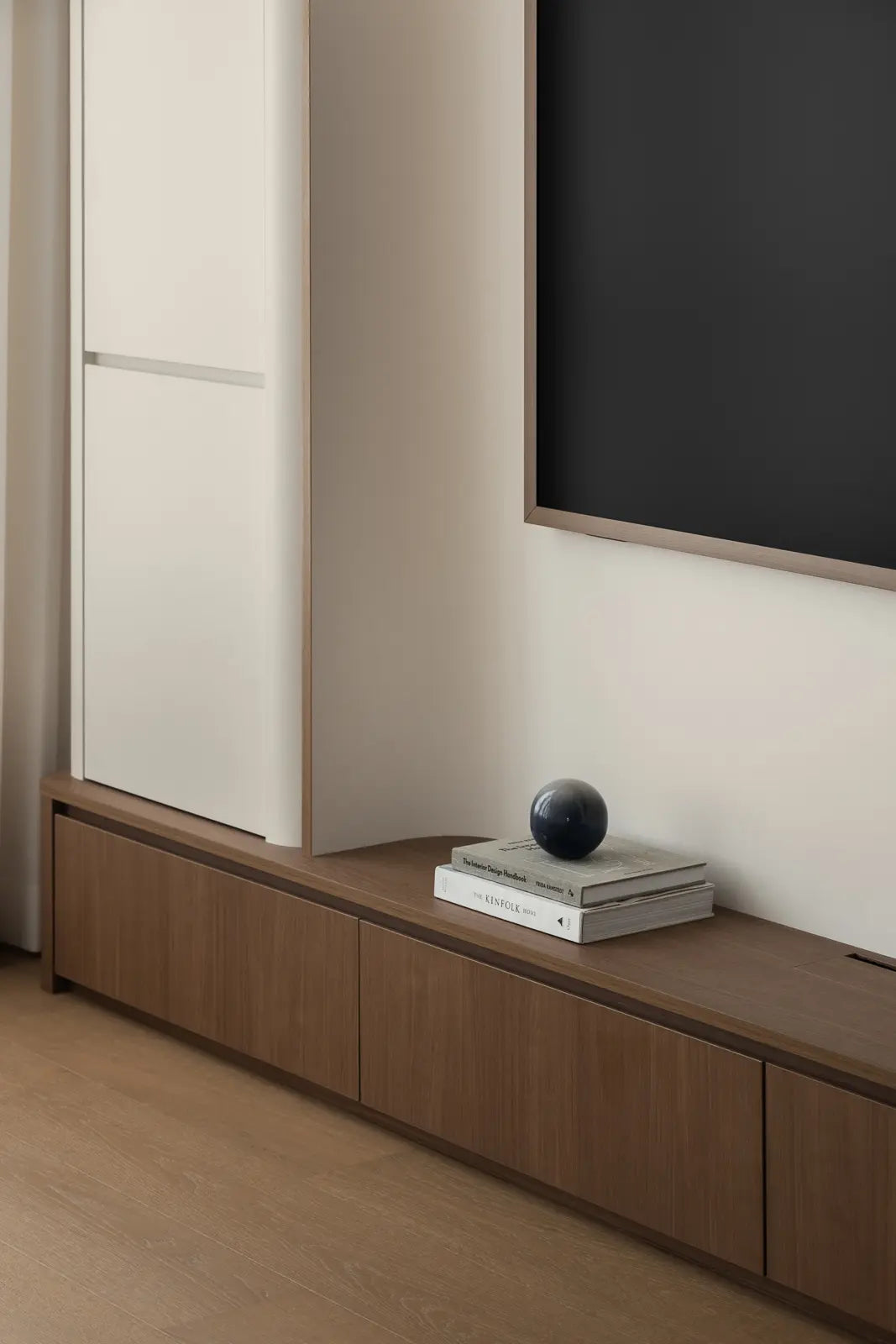 Minimalist living room with a curved TV feature wall and light wood flooring