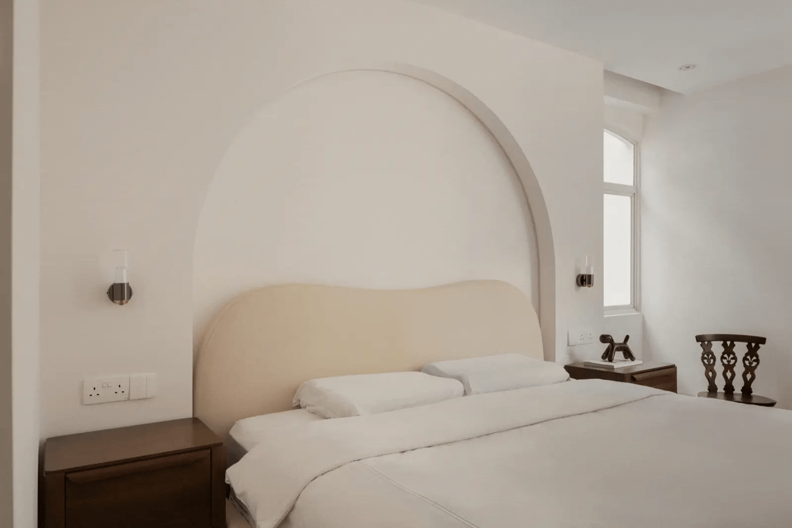 Minimalist bedroom with an arched feature wall and wall sconces