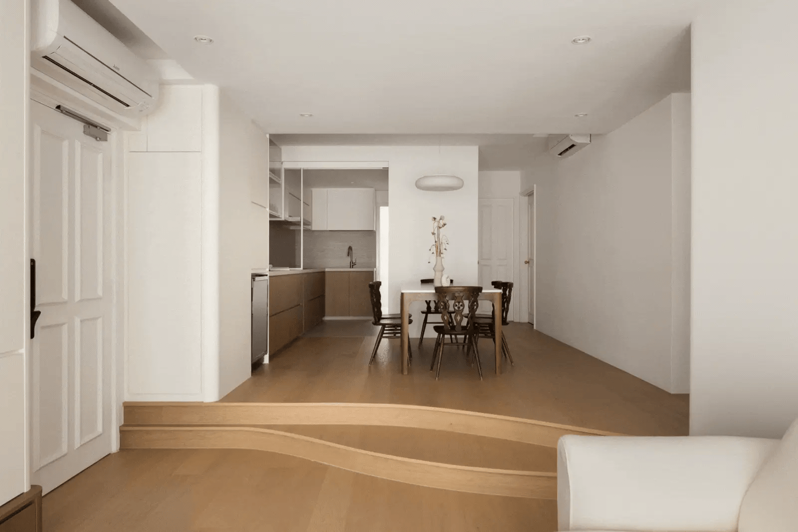 Minimalist dining room with curved steps and light wood flooring