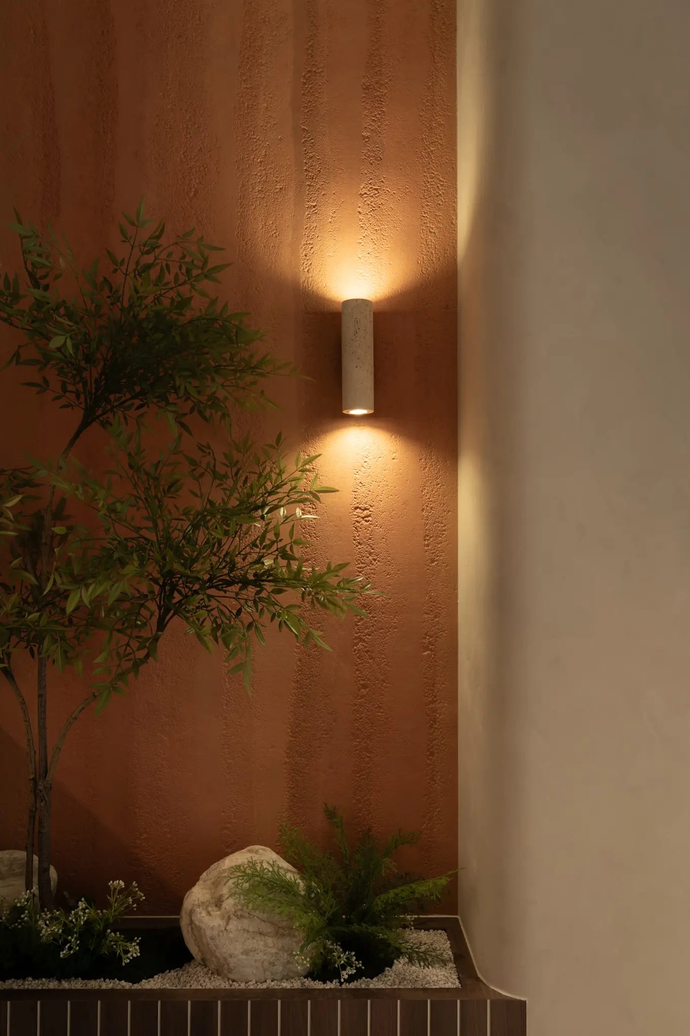 Living room with textured wall finish, natural materials and warm lighting from wall sconce