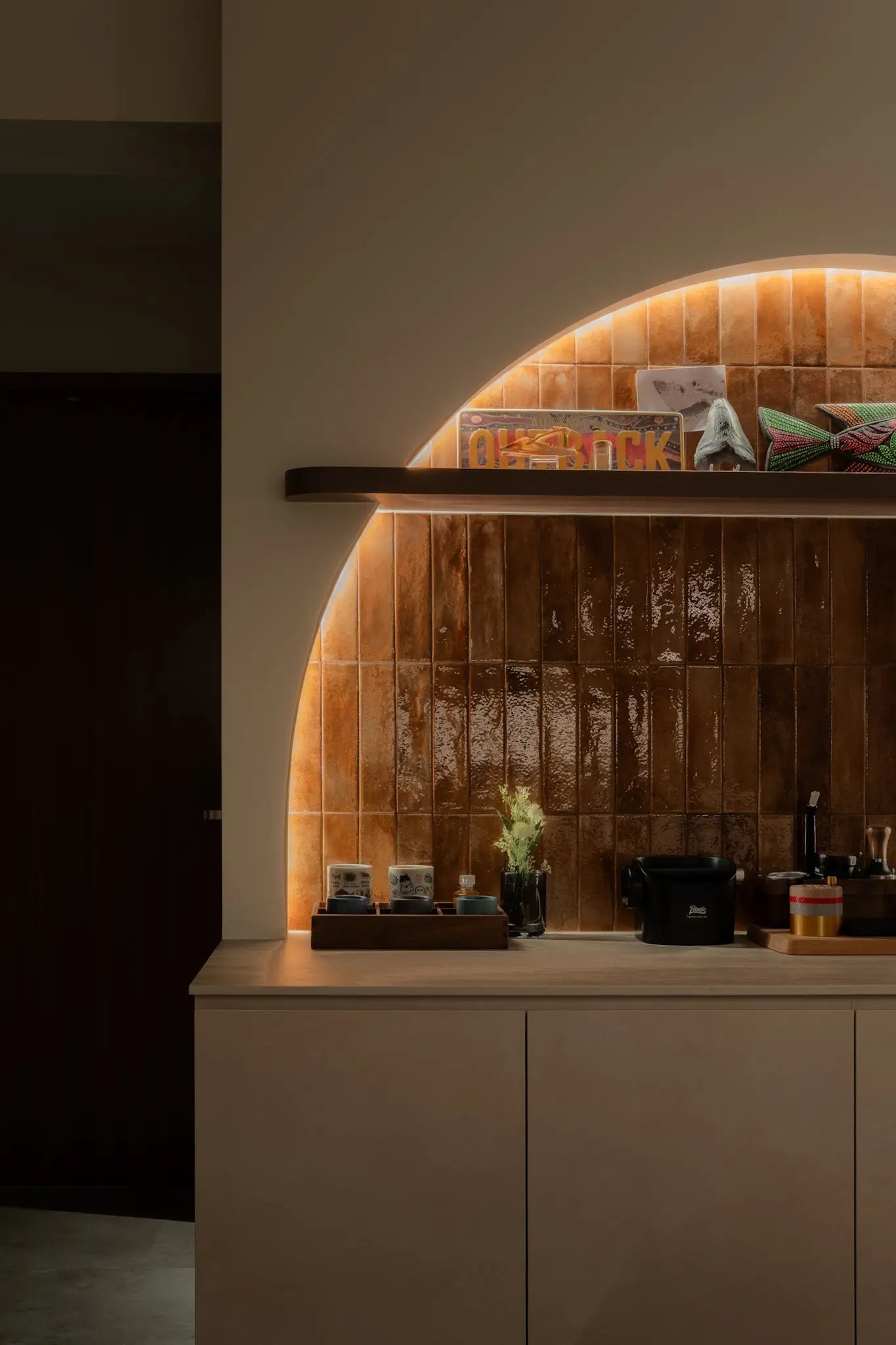 Modern kitchen with a arch feature wall, brick-red subway tile backsplash and neutral-toned cabinetry
