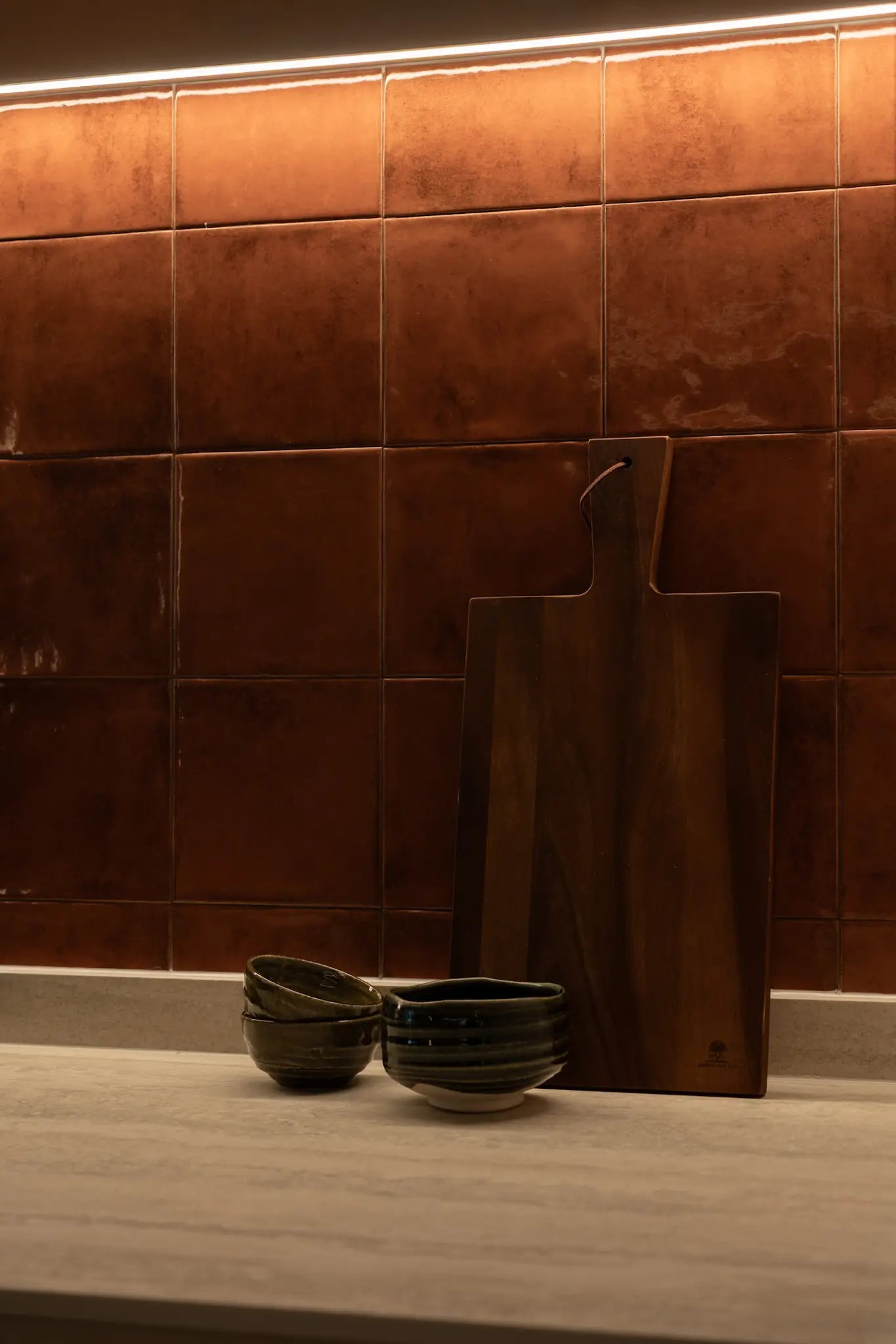 Modern kitchen with terracotta-toned square tile backsplash and sintered stone counterop